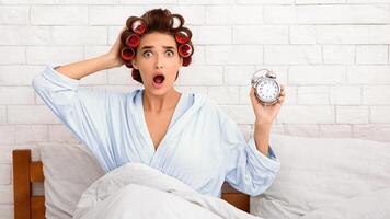 Oversleeping. Shocked Overslept Woman Holding Alarm Clock Being Late For Work Sitting In Bed At Home In The Morning, Looking At Camera. Deadline, Not In Time Concept. Panorama photo