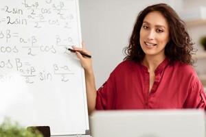 E-learning During Covid Lockdown. College professor teaching mathematics on web, conducting online class from home. Portrait of millennial teacher explaining math problems on internet using pc photo