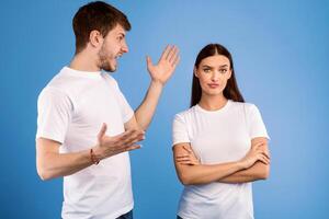 Relationship Problems. Young man arguing with his girlfriend who ignoring him, isolated over purple studio wall photo