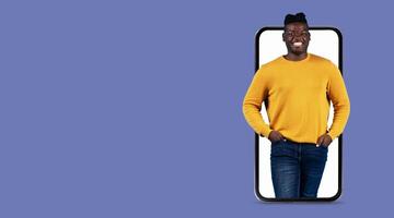 A person stands confidently with hands in pockets, displayed on a large smartphone screen. This representation highlights modern communication through technology. photo