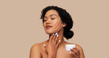A woman practices self-care by applying skin care cream to her face. She enjoys a relaxing moment of beauty routine in a tranquil setting with neutral tones. photo