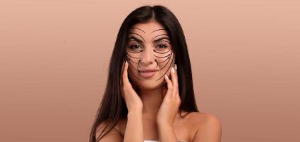 A woman is engaged in her skin care routine, using facial markings to enhance her beauty. Her relaxed expression suggests enjoyment and pampering in a tranquil, empty space. photo