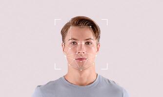 A young man stands against a plain backdrop while facial recognition technology highlights his features. This illustration shows the process of digital identification accurately. photo