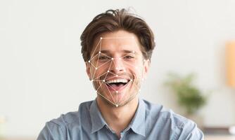 A man with a joyful expression showcases facial recognition technology. The system displays geometric patterns on his face, illustrating the identification process in a modern environment. photo