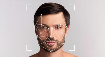 A man is captured against a light background with a geometric overlay on his face. This technology highlights facial recognition features commonly used for identification purposes. photo