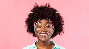 A person with a joyful expression stands against a pink background. Facial identification technology analyzes their features while they smile, showcasing advanced recognition capabilities. photo