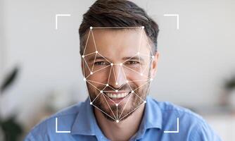 A man is smiling while a facial recognition system maps his features. The setting is bright and modern, providing an excellent backdrop for technology demonstration. photo