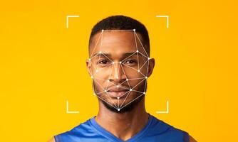 A man poses against a vibrant yellow background while facial recognition technology is applied to his face. The geometric overlay illustrates digital identification features. photo