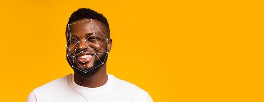 A smiling man with facial recognition markers overlayed, showcasing advanced identification technology. The bright yellow background emphasizes the subject's expression and the tech's features. photo