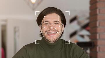 A smiling individual is displayed within a digital facial recognition framework, showcasing advanced identification technology. The setting suggests a modern environment focused on innovation. photo