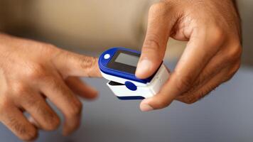 Male hands using modern pulse oximeter, closeup photo, copy space. Unrecognizable middle-eastern man putting clip-like small device for blood oxygen, saturation measuring, cropped photo