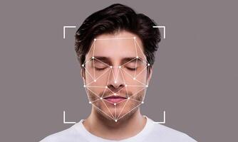 A person with closed eyes is engaged in facial recognition technology. An overlay of geometric shapes indicates the mapping of facial features for identification purposes. photo