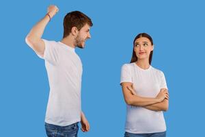 Relationship Problems. Young man trying to hit his girlfriend who ignoring him, isolated over purple studio wall photo