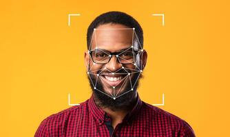 A smiling person with glasses poses against a bright yellow backdrop, featuring facial recognition markers superimposed on their face, illustrating identification technology in action. photo