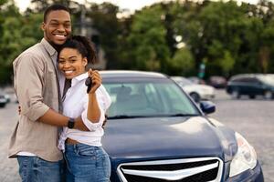 New Car. Happy African American Couple Showing Automobile Key Smiling To Camera Hugging Standing Near Auto Outdoors. Vehicle Dealership, Purchase And Leasing Concept photo