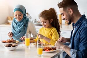 Breakfast Time. Middle Eastern Family Of Three Enjoying Tasty Food In Kitchen, Happy Arabic Parents And Their Little Daughter Sitting At Table, Having Delicious Meal In The Morning, Closeup photo