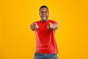 Hey, You. Emotional African American Man Pointing Fingers With Both Hands Looking At Camera And Shouting Standing On Yellow Studio Background. You're Next, I Choose You Concept photo