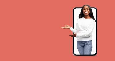A cheerful woman appears to be presenting information or ideas through a large smartphone screen. She stands out with a friendly gesture, showcasing the use of technology for communication. photo