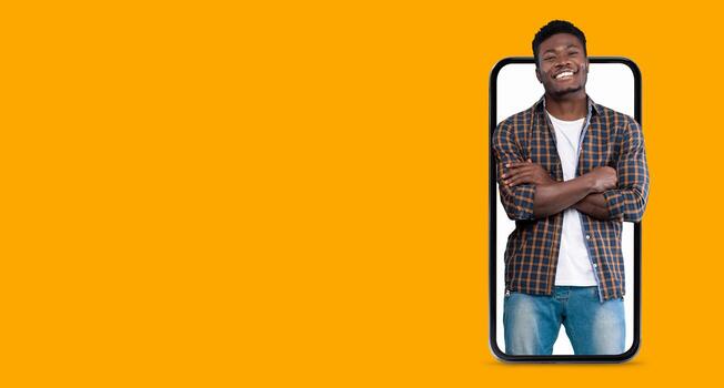 A person stands confidently with crossed arms, smiling at the camera, while appearing to be engaged with a smartphone featuring a large screen. The background is bright and inviting. photo