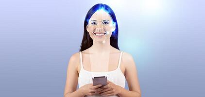 A woman smiles while holding a smartphone, showcasing advanced facial recognition technology. She appears engaged in a modern setting, highlighting the importance of digital identification. photo