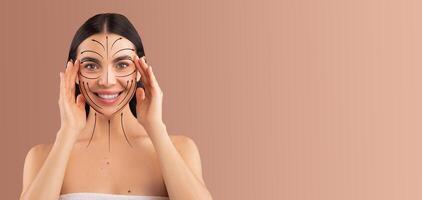 A woman is enjoying her beauty routine, using her hands to gently apply skin care techniques. She is isolated against a soft backdrop, emphasizing her joyful expression and commitment to self-care. photo