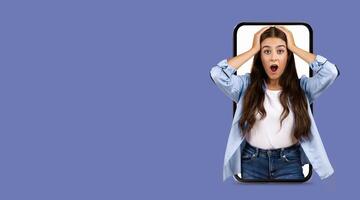 A young woman shows an expression of shock and disbelief while using a large smartphone. She seems engaged with an online application, highlighting modern communication. photo