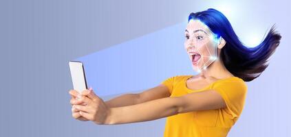 A woman enthusiastically engages with her smartphone, showcasing face recognition technology. The background is minimalistic and gray, emphasizing her expression and the tech. photo
