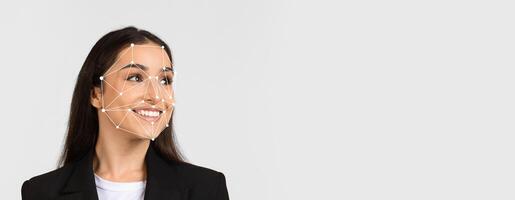 A woman with long hair smiles while facial recognition technology overlays her features. The background is blank, emphasizing the technology's application in identification. photo