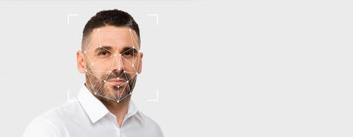 A man poses against a blank background while facial recognition technology scans his face for identification purposes. This highlights current trends in biometric security measures. photo