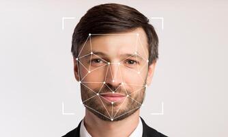 A man with a neutral expression stands against a plain background, displaying facial recognition technology that detects his facial features for identification purposes. photo