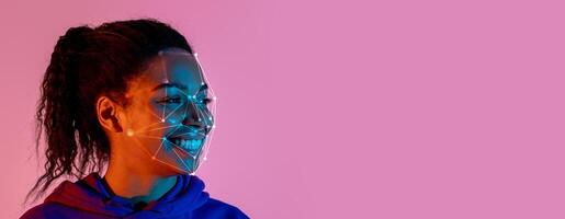 A young person displays a joyful expression while facing the camera, illuminated by colorful lights. Facial recognition technology is showcased through digital graphics on their face. photo