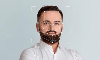 A man with a beard displays a neutral expression while facial recognition technology analyzes his features on a plain background. This modern approach enhances identification processes. photo