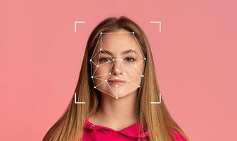 A young woman stands confidently in front of a pink backdrop, her face marked by facial recognition technology. The design features connecting lines and points highlighting facial features. photo