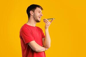 Phone Call, Mobile Communication And Voice Assistant Concept. Smiling Bearded Man Talking On Smartphone Using Loudspeaker Mode, Guy Standing Isolated Over Blue Studio Background, Copy Space photo