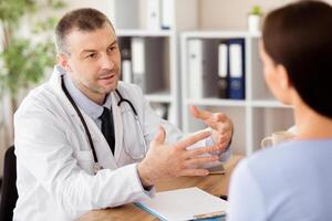 Medicine And Health Care Concept. Doctor and patient discussing something, sitting at the table, gesturing photo