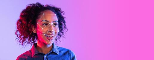 A person with curly hair smiles while facial recognition technology analyzes their features. The background has a vibrant gradient, enhancing the technological theme and atmosphere. photo