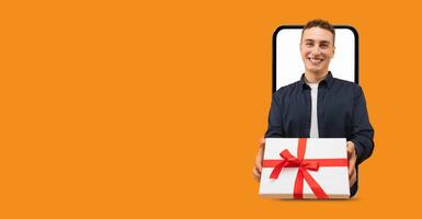 A smiling individual is holding a wrapped gift box with a red bow, appearing to come out of a smartphone screen. The background features a vibrant, solid color, emphasizing the joyful moment. photo