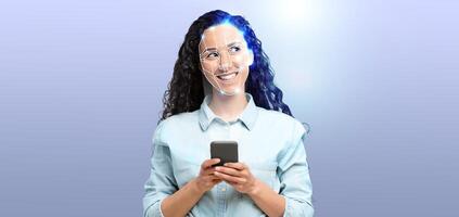 A woman with curly hair smiles while holding a smartphone. Her face is illuminated to showcase facial recognition technology, symbolizing modern identification methods in action. photo