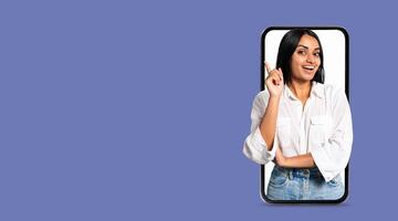A young person with a friendly expression is gesturing while holding a smartphone. The background features a solid color, emphasizing the connection to social media and communication technology. photo