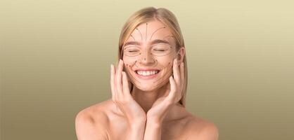 A young woman is smiling with closed eyes while applying skincare products to her face. She is in a calm, isolated environment with a smooth texture in the background, perfect for relaxation. photo