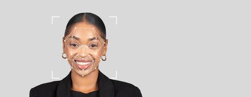 Subject demonstrates facial recognition technology with a joyful expression. The background is gray and empty, emphasizing the person and features of the identification technology. photo