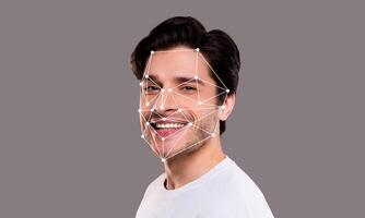 A man displays a joyful expression while facial recognition technology analyzes his features. The background is neutral, emphasizing the technological aspect of identification systems. photo
