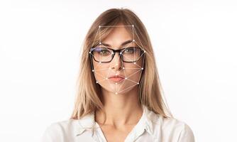 A woman with glasses is featured against a plain background, showcasing a facial recognition overlay highlighting key facial features. This technology emphasizes identification capabilities. photo