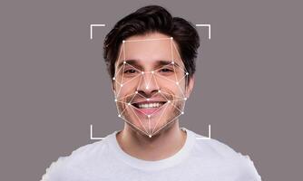 A young man is smiling while being analyzed by facial recognition technology. The geometric overlay highlights key facial features, illustrating advanced identification capabilities. photo