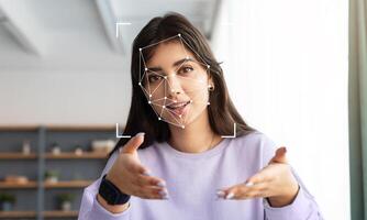 A person explains a concept while facial recognition technology analyzes their features. The setting is modern and well-lit, focusing on the relationship between technology and human interaction. photo