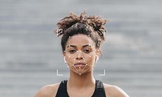 A person stands in a relaxed posture, with their face framed by a technology overlay for identification. The background is softly blurred, creating a focus on the subject's features. photo