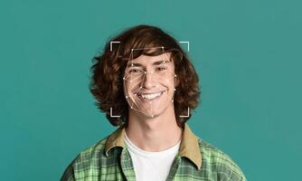 A young person with curly hair is smiling, with facial identification markers displayed around their face. The solid background emphasizes the subject and technology used in facial recognition. photo
