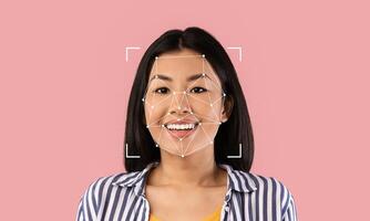 A young woman smiles while facial recognition technology identifies her features. This highlights advancements in identification methods and their implications in various fields. photo