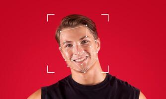 Facial recognition technology highlights a young man smiling against a vibrant red background. The geometric overlays represent identification features for tech applications in security. photo