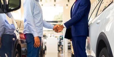 Cropped Image Of Black Car Seller Shaking Hands With Client After Successful Deal, Unrecognizable Salesman Selling Auto To Customer In Modern Dealership Center, Handshaking After Agreement, Side View photo